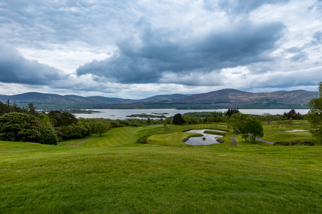 An Irish golf hole running toward mountains beneath dramatic clouds