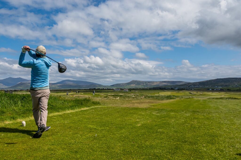 Golfer hitting a tee shot across a links course in County Kerry, Ireland