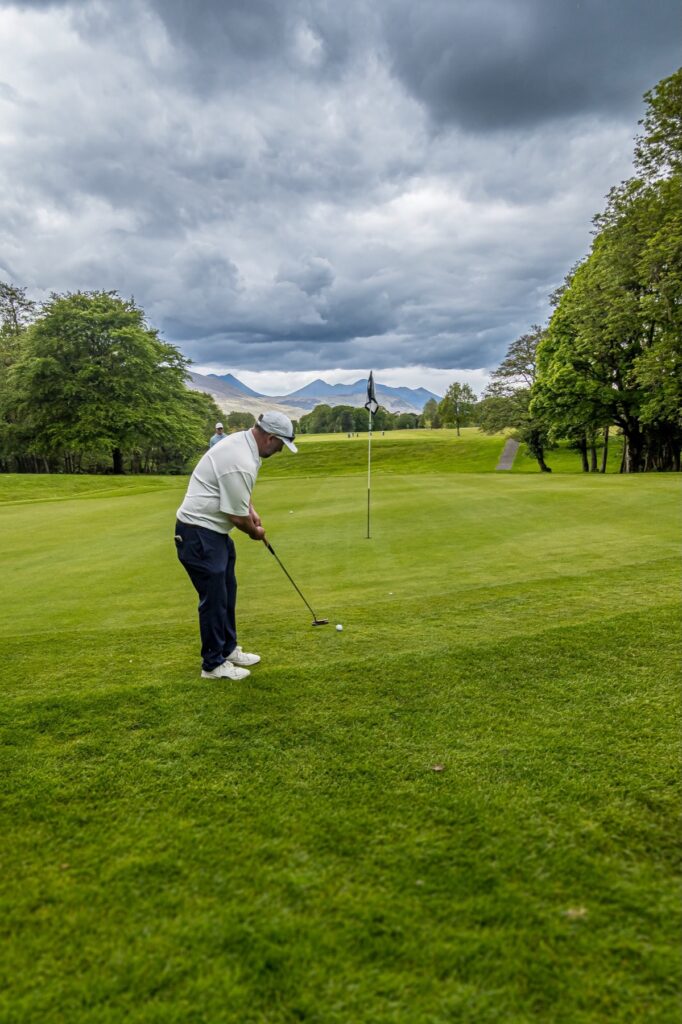Golfer putting with the MacGillycuddy's Reeks behind the green in Killarney