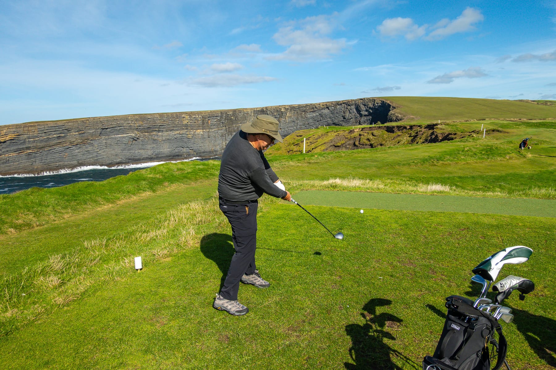 A golfer preparing a tee shot beside the cliffs at Kilkee
