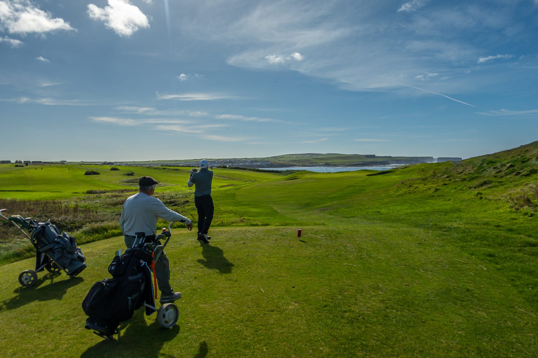 Golfers and their trolleys on a coastal fairway during the Kilkee extension