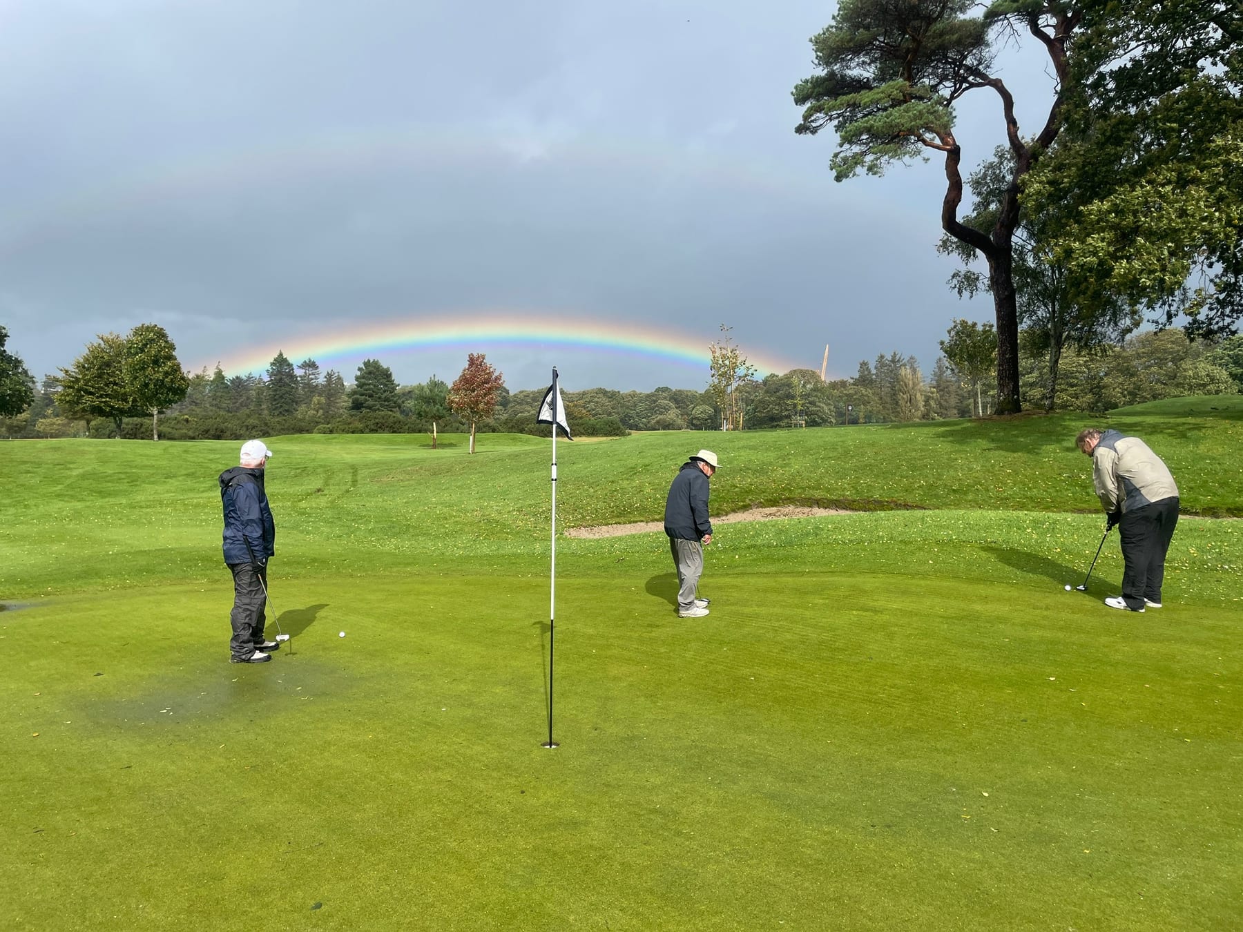A rainbow behind golfers putting on a green during the Ireland trip